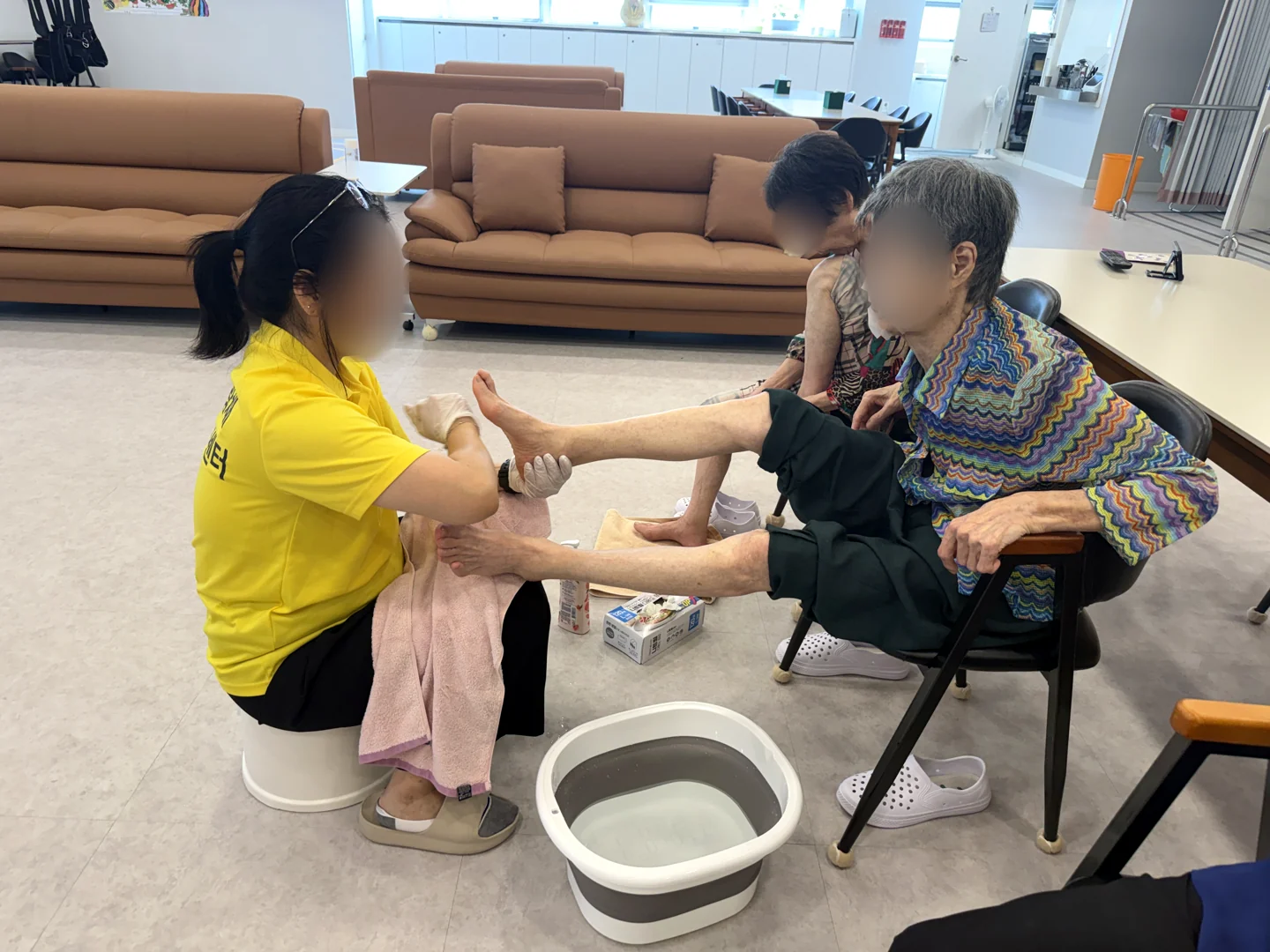 족욕 후 직원이 어르신의 발을 수건으로 닦으며 돌보는 모습