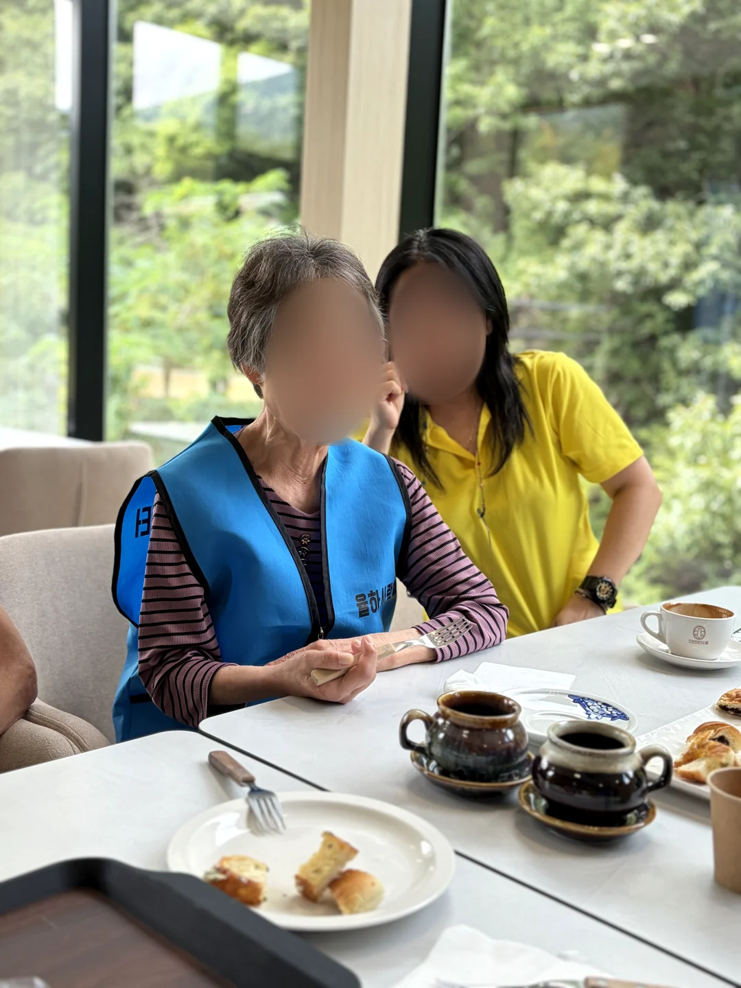 바깥 나들이 중 창가에 앉아 직원과 함께 시간을 보내는 어르신