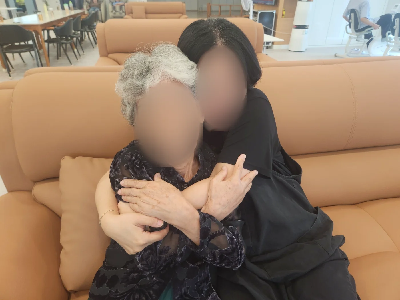 직원과 어르신이 소파에서 다정하게 포옹하는 실제 모습